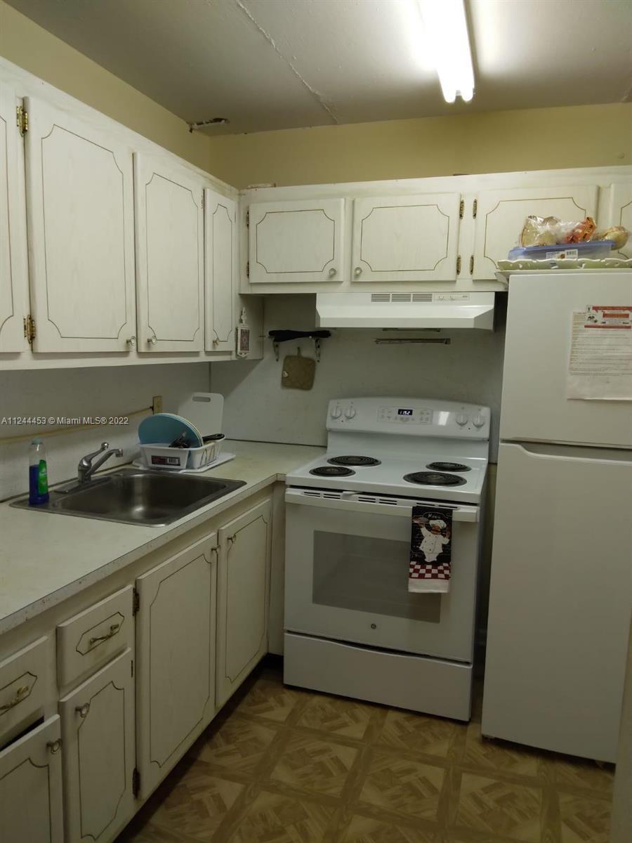 A kitchen features white cabinets, a stainless steel sink, a white stove, and a refrigerator — 206 Sheffield I # 206, West Palm Beach FL 33417, WEST PALM BEACH, FL