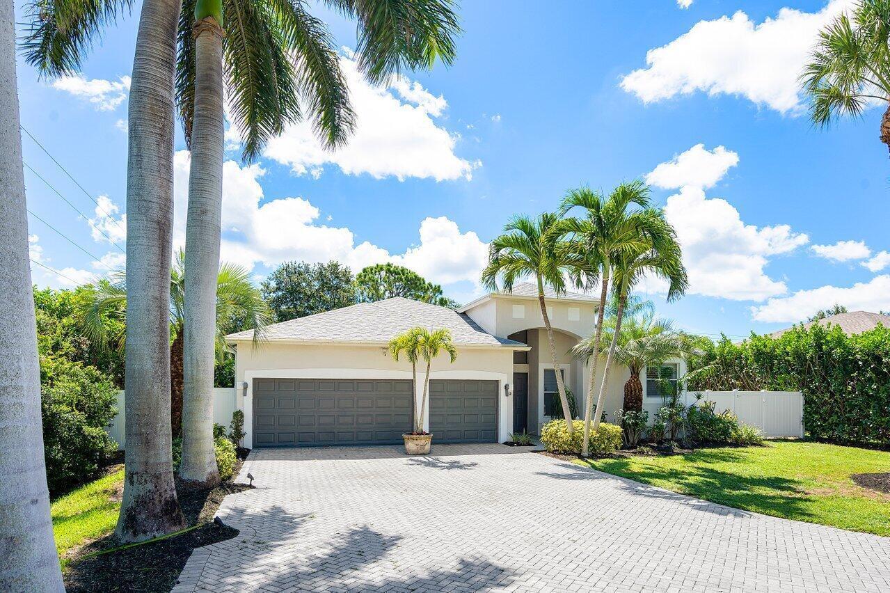 A single-story house with a two-car garage, paved driveway, and palm trees under a blue sky — 50 Lake Eden Drive, Boynton Beach FL 33435, BOYNTON BEACH, FL
