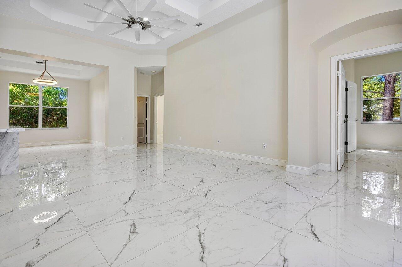 A bright, empty room features white marble-look tile flooring, a tray ceiling, and large windows — 50 Lake Eden Drive, Boynton Beach FL 33435, BOYNTON BEACH, FL