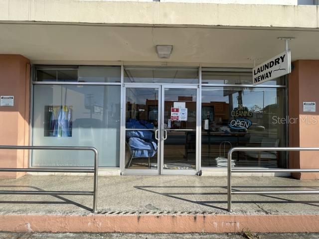 The exterior of a commercial storefront features a glass door entrance and a laundry sign — 400 AV. ING. MANUEL DOMENECH, SAN JUAN, PR