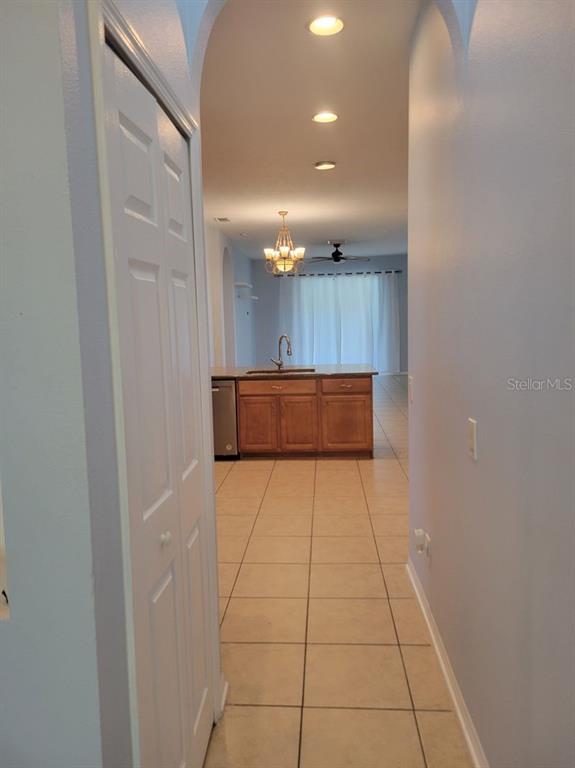 A hallway leads to a kitchen with wooden cabinets and tile flooring — 30541 NORSEMAN PLACE, WESLEY CHAPEL, FL