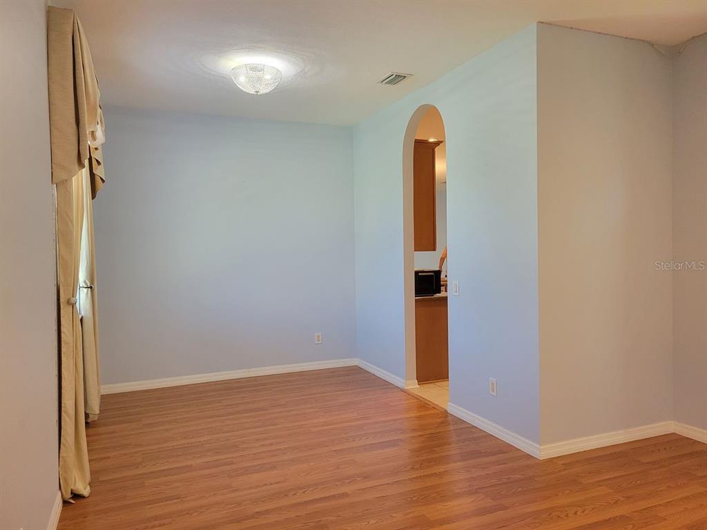 An empty room with light blue walls, wood-look flooring, and an arched doorway — 30541 NORSEMAN PLACE, WESLEY CHAPEL, FL