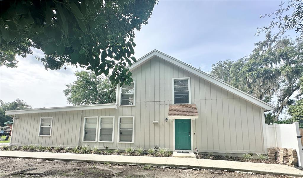 A two-story house with light-colored vertical siding, a green front door, and a sidewalk — 122 S BULOVA DRIVE, APOPKA, FL