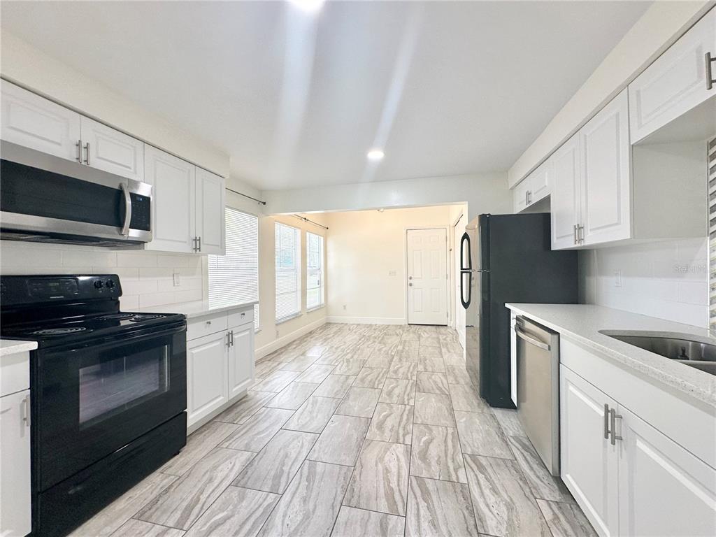 A kitchen with white cabinets, black appliances, and light-colored wood-look tile flooring — 122 S BULOVA DRIVE, APOPKA, FL