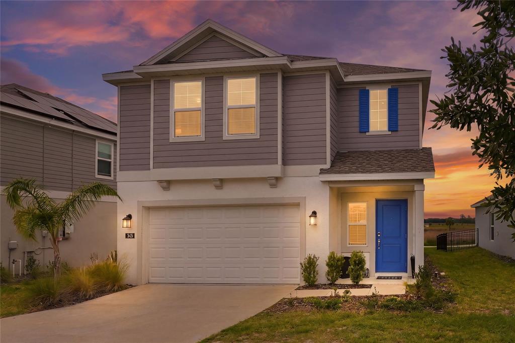 A two-story house with gray siding, a white garage, and a bright blue front door — 545 BELL PRAIRIE CIRCLE, LAKE WALES, FL