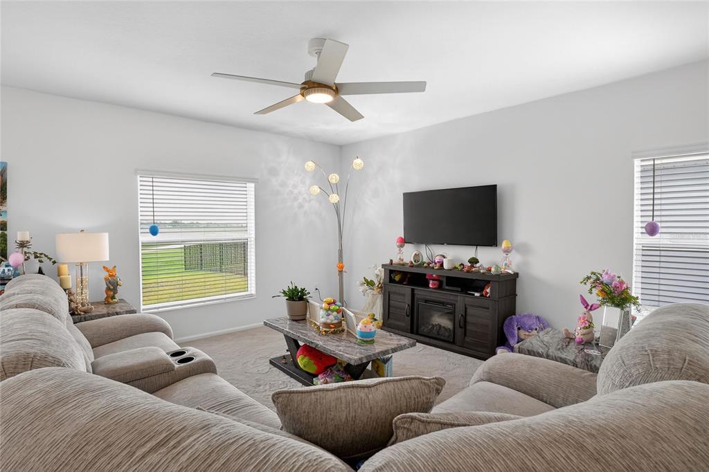 A living room features a sectional sofa, a television on a media console, and two windows — 545 BELL PRAIRIE CIRCLE, LAKE WALES, FL