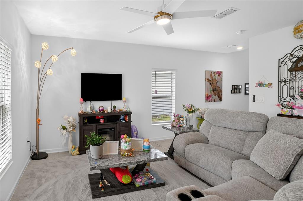 A living room features a grey sectional sofa, a television on a console, and carpeting — 545 BELL PRAIRIE CIRCLE, LAKE WALES, FL