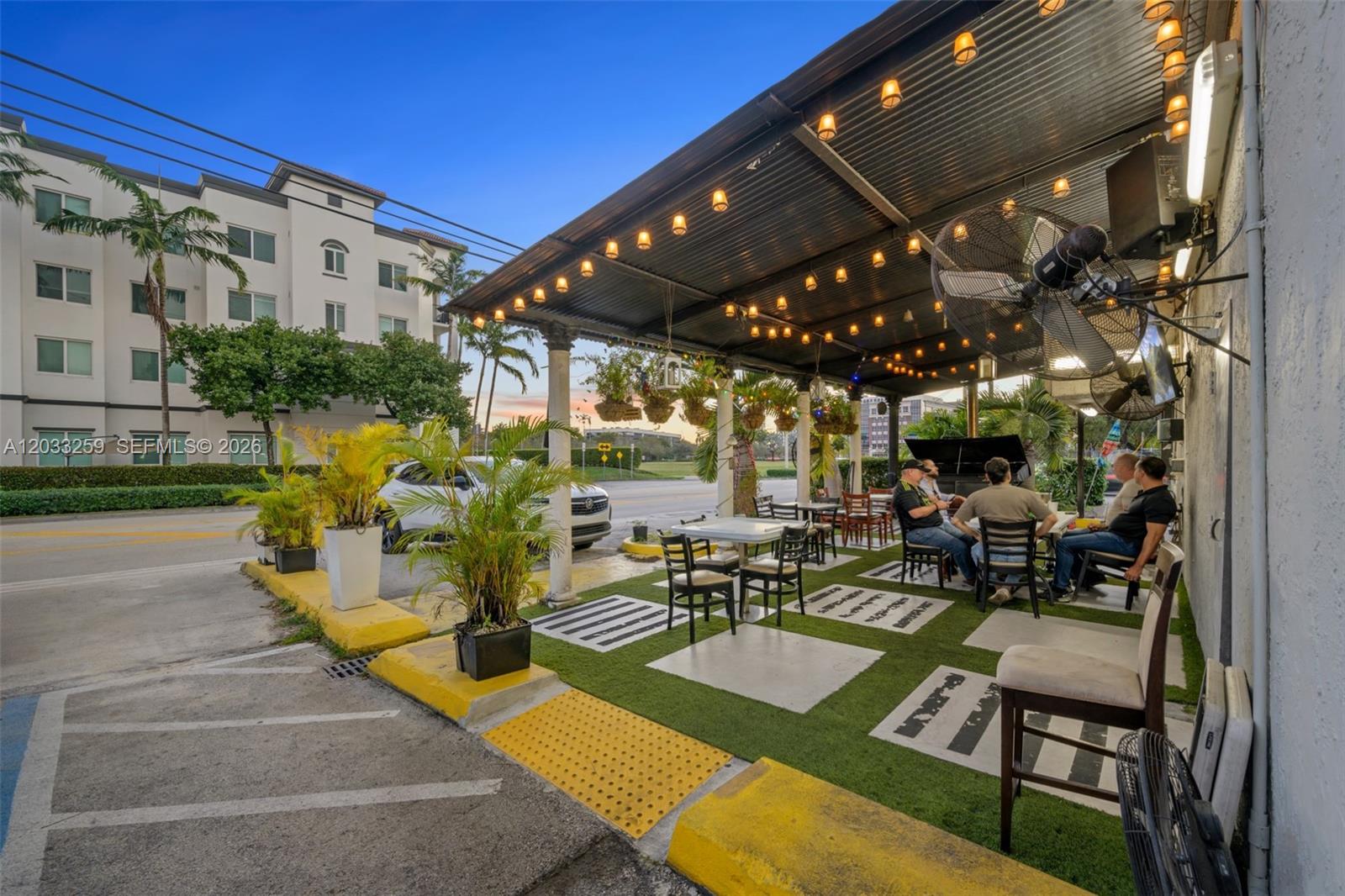 An outdoor patio area features a covered seating space with artificial turf and string lights — 5405 NW 82nd Ave, Doral FL 33166, DORAL, FL