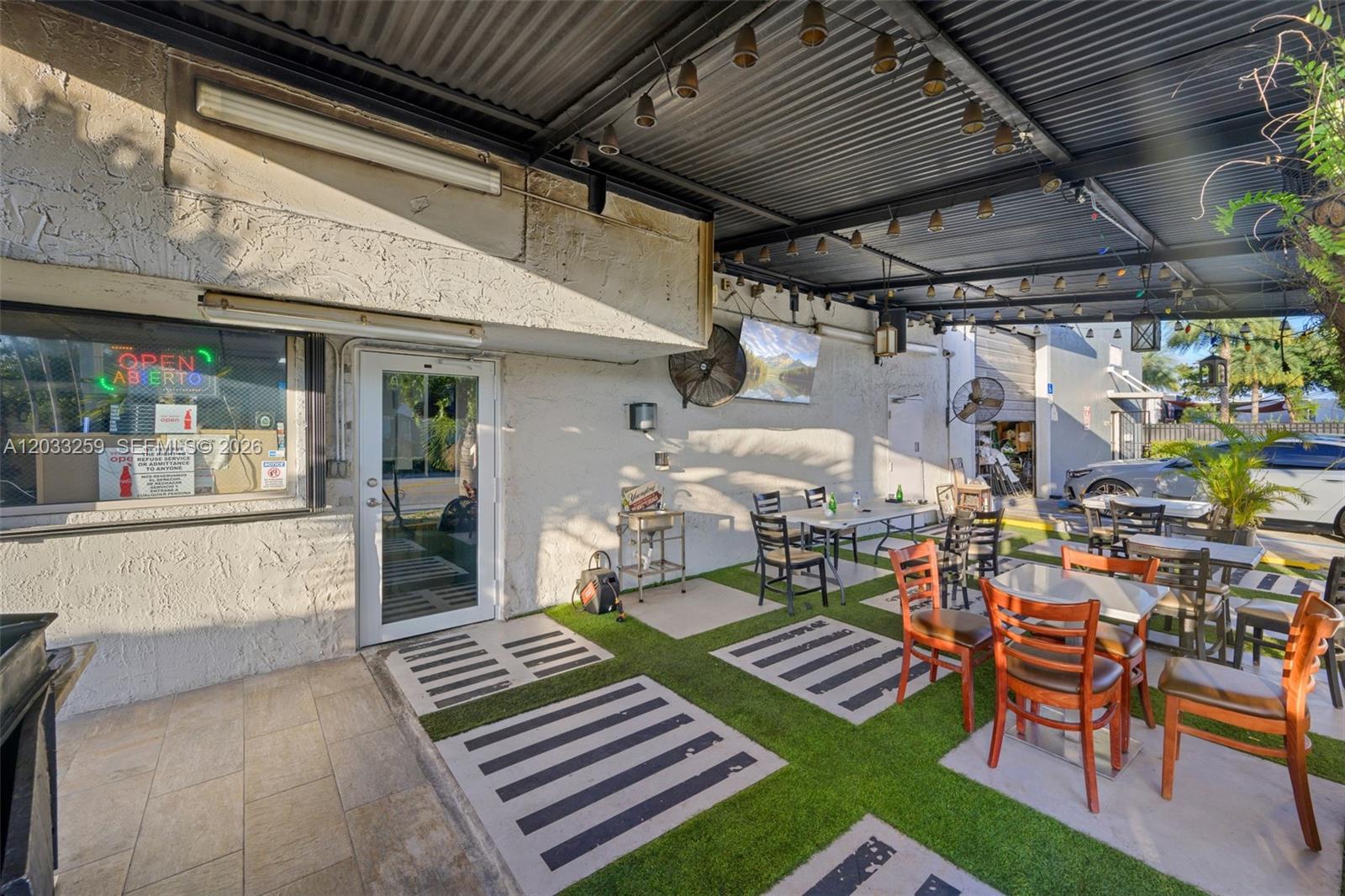 An outdoor patio area features tables, chairs, artificial turf, and a covered metal roof — 5405 NW 82nd Ave, Doral FL 33166, DORAL, FL