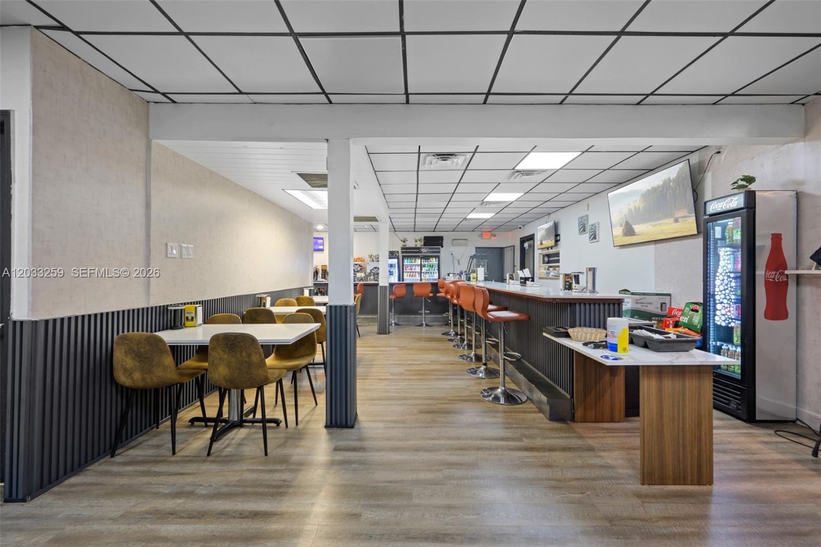 This commercial space features a bar with stools, dining tables, and a Coca-Cola refrigerator — 5405 NW 82nd Ave, Doral FL 33166, DORAL, FL