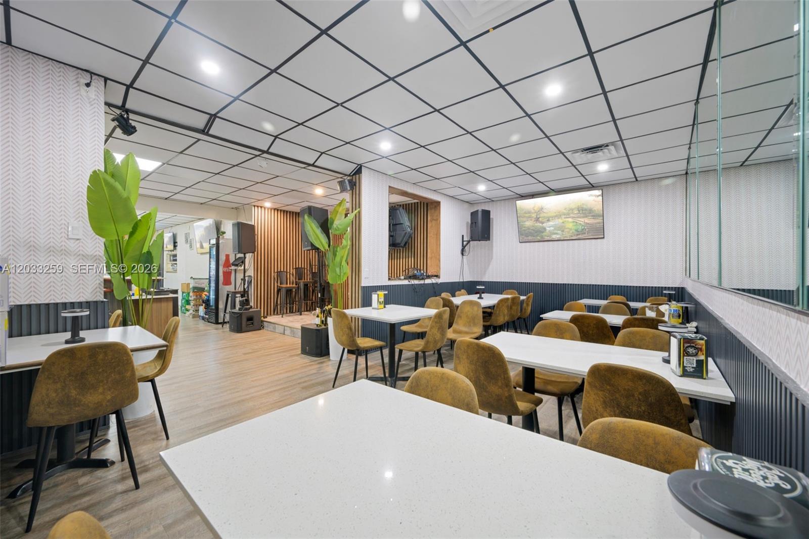 A restaurant interior features white tables, mustard-colored chairs, a drop ceiling, and wood-paneled walls — 5405 NW 82nd Ave, Doral FL 33166, DORAL, FL