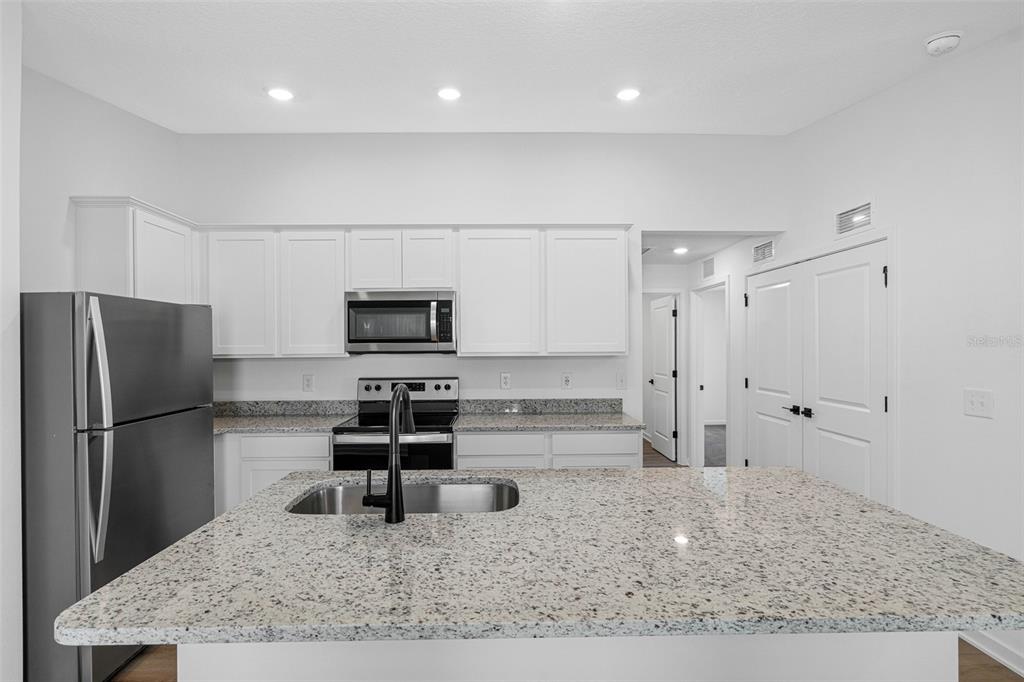 A kitchen features white cabinets, granite countertops, stainless steel appliances, and a central island — 525 BLACKTHORN DRIVE, LAKELAND, FL