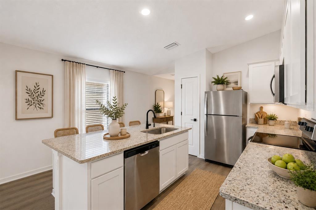 A kitchen features white cabinets, granite countertops, stainless steel appliances, and a central island — 525 BLACKTHORN DRIVE, LAKELAND, FL