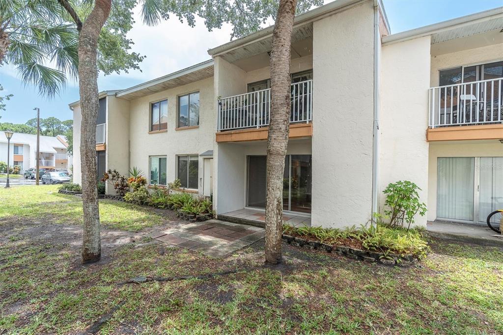The exterior of a two-story apartment building features balconies, sliding glass doors, and palm trees — 675 99TH AVENUE N UNIT 102, ST PETERSBURG, FL