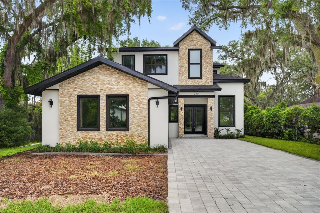 A two-story house with stone veneer, white stucco walls, and a paved driveway — 240 N PHELPS AVENUE, WINTER PARK, FL
