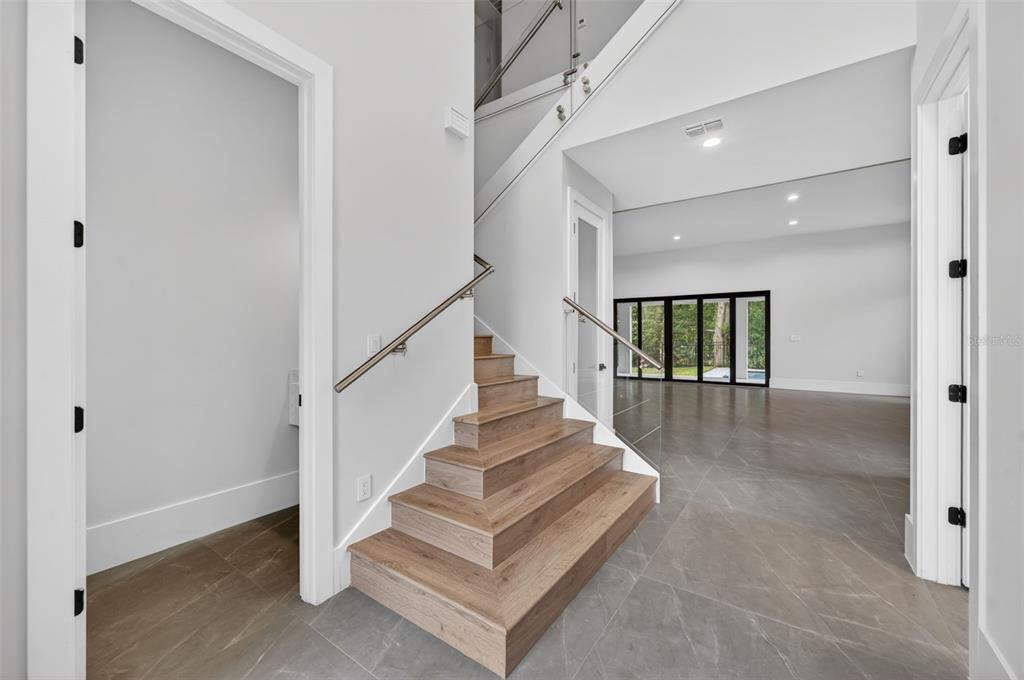 A modern staircase with wood treads and glass railings sits between two doorways — 240 N PHELPS AVENUE, WINTER PARK, FL