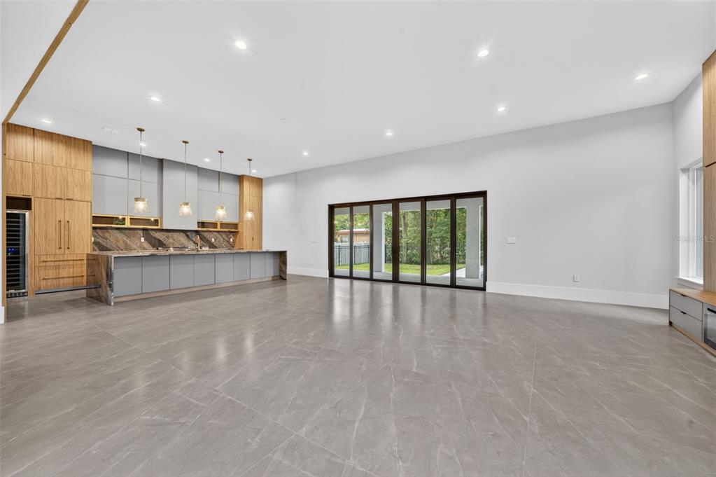 A modern open-concept kitchen and living area features gray tile floors and large glass doors — 240 N PHELPS AVENUE, WINTER PARK, FL