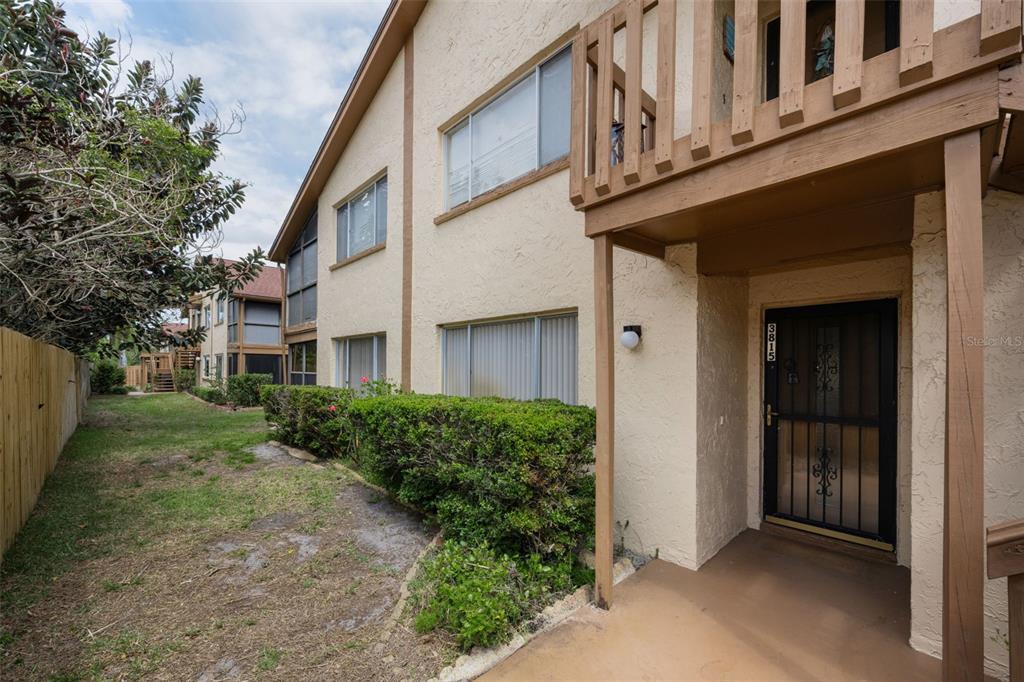 A two-story apartment building exterior with a wooden balcony, a front door, and landscaping — 3815 PENRICK DRIVE UNIT 0, NEW PORT RICHEY, FL