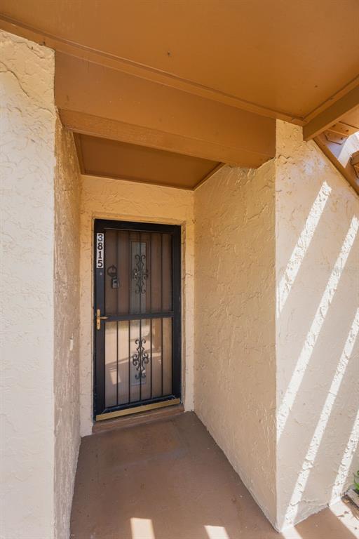 A recessed entryway features a black metal security door with decorative scrollwork and a lockbox — 3815 PENRICK DRIVE UNIT 0, NEW PORT RICHEY, FL