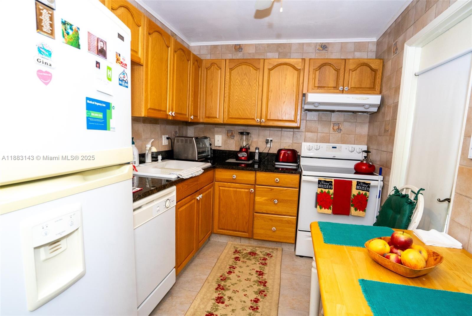 A kitchen features wood cabinets, a white refrigerator, a dishwasher, and a small dining table — 1000 NE 14th Ave # 207, Hallandale Beach FL 33009, HALLANDALE BEACH, FL