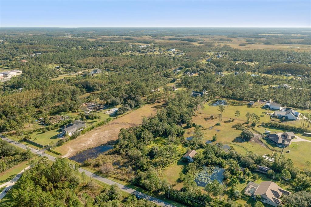 An aerial view shows a rural landscape with scattered houses, ponds, and dense forest areas — BABBITT AVENUE, ORLANDO, FL