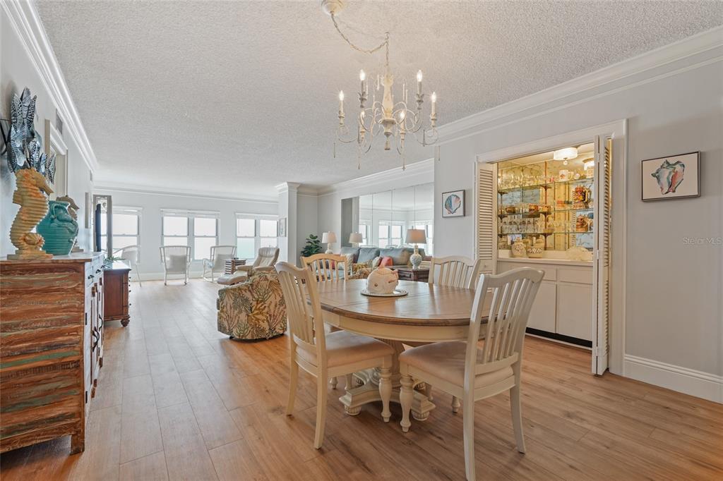 A dining area with a wooden table and chairs sits adjacent to a living room — 4950 GULF BOULEVARD UNIT 605, ST PETE BEACH, FL