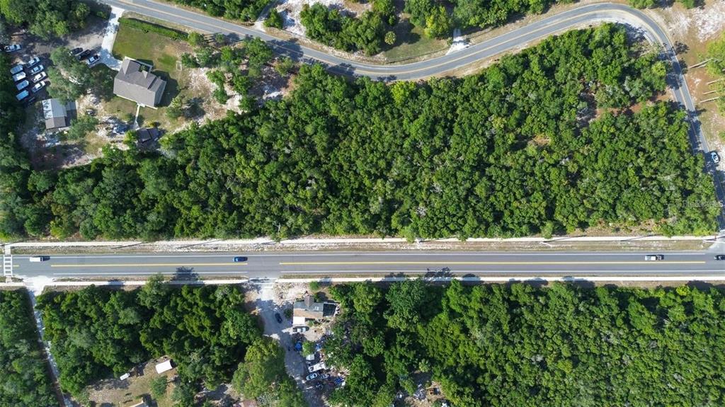 An aerial view shows a wooded lot bordered by a road and nearby houses — DOYLE ROAD, DELTONA, FL