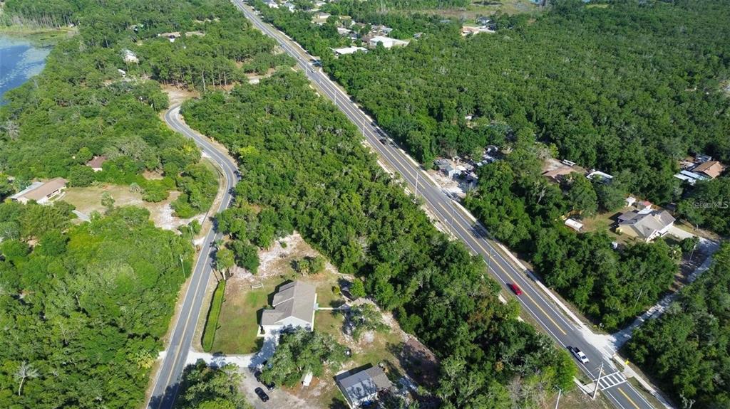 An aerial view shows a road winding through a wooded area with scattered residential houses — DOYLE ROAD, DELTONA, FL
