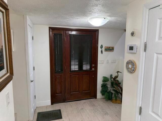 An entryway features a dark wood front door, light wood flooring, and a ceiling light — 709 Savannah Street, Fort Pierce FL 34982, FORT PIERCE, FL