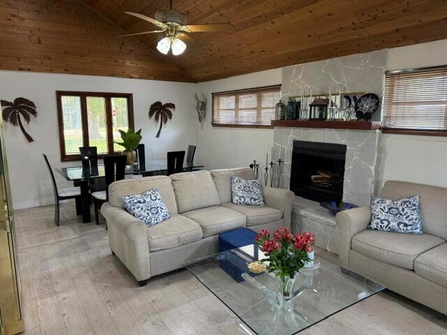A living room with a stone fireplace, beige sofas, and an adjacent dining area — 709 Savannah Street, Fort Pierce FL 34982, FORT PIERCE, FL