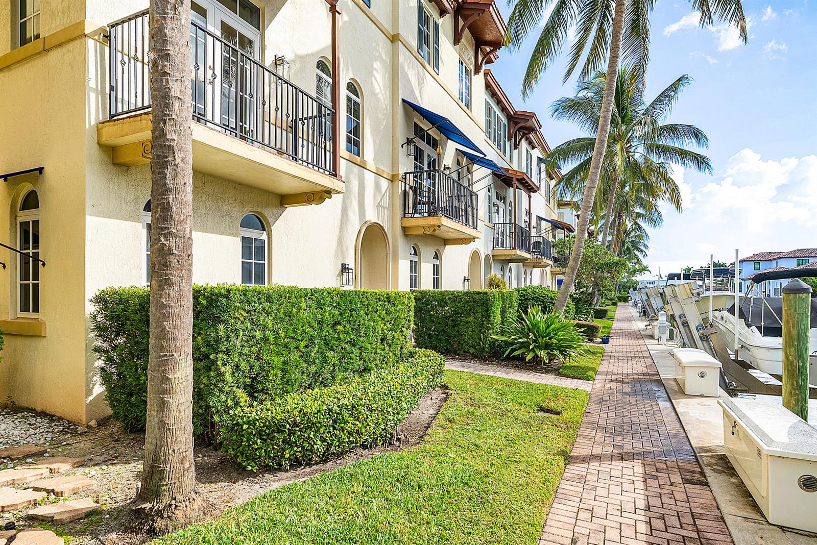 A row of yellow townhouses with balconies sits beside a brick walkway and boat slips — 824 Virginia Garden Drive, Boynton Beach FL 33435, BOYNTON BEACH, FL