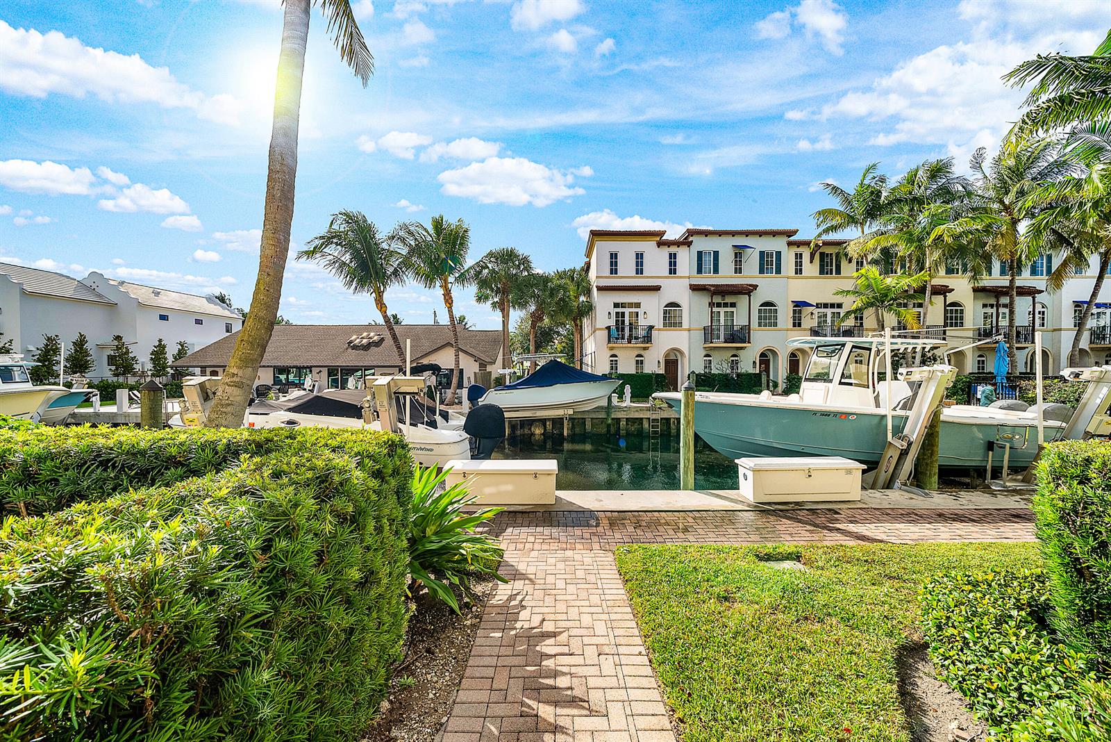 A brick walkway leads to a boat slip with docked motorboats in front of townhouses — 824 Virginia Garden Drive, Boynton Beach FL 33435, BOYNTON BEACH, FL