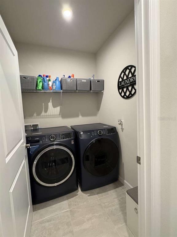 A laundry room features dark blue appliances, a wire shelf with storage bins, and tile flooring — 1982 W PALMS DRIVE, PORT CHARLOTTE, FL