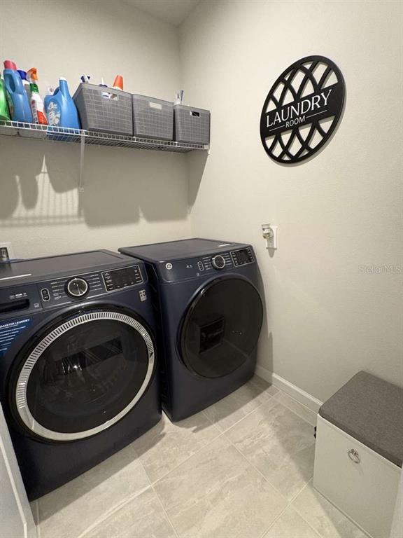 A laundry room features dark blue appliances, a wire shelf with storage bins, and wall decor — 1982 W PALMS DRIVE, PORT CHARLOTTE, FL