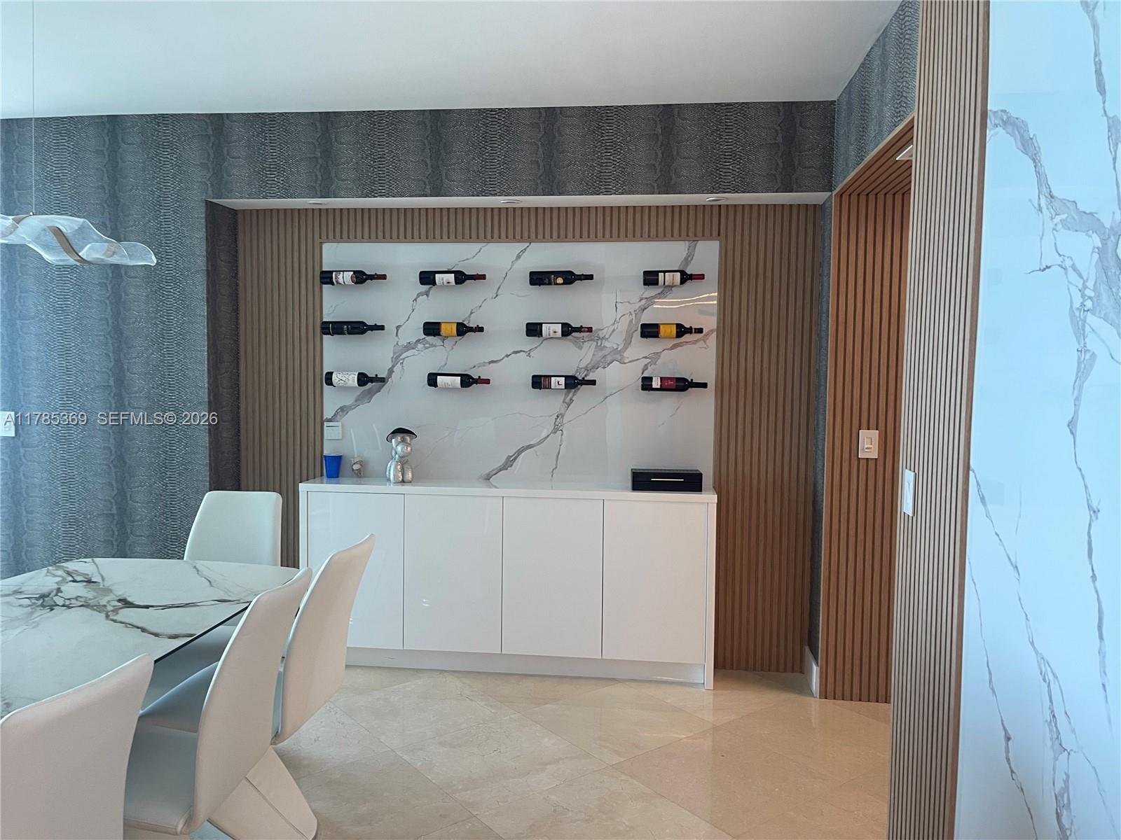 A dining room features a marble-topped table, white chairs, and a wall-mounted wine display — 3101 S Ocean Dr # 1707, Hollywood FL 33019, HOLLYWOOD, FL