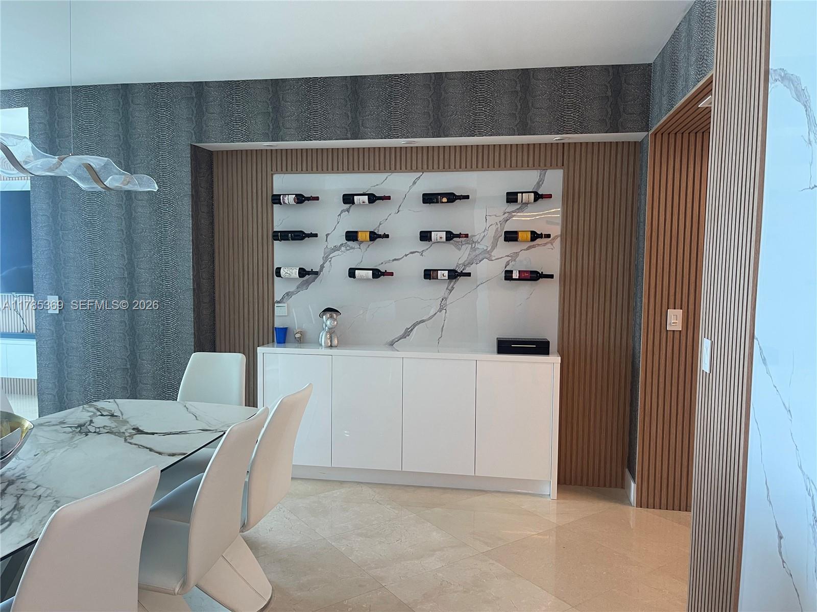 A dining room features a marble-topped table, white chairs, and a built-in wine display wall — 3101 S Ocean Dr # 1707, Hollywood FL 33019, HOLLYWOOD, FL