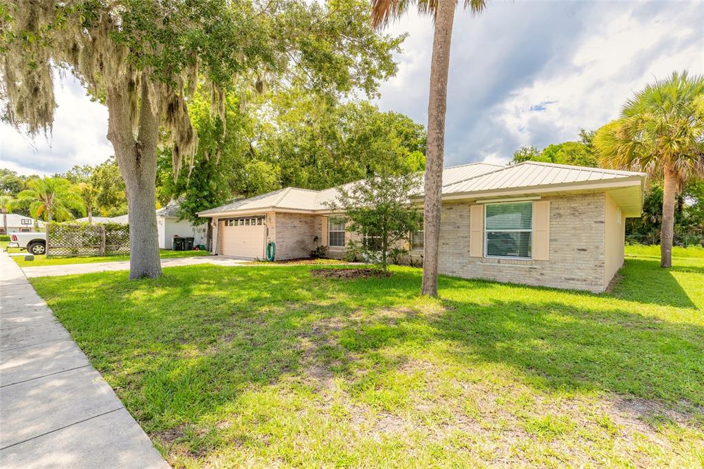A single-story brick house with a metal roof and a front-facing garage sits on a lawn — 816 IRON HORSE ROAD, DAYTONA BEACH, FL