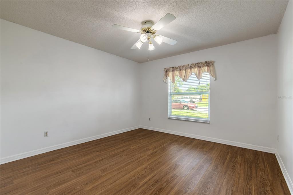 An empty bedroom with white walls, wood-look flooring, a ceiling fan, and a single window — 816 IRON HORSE ROAD, DAYTONA BEACH, FL