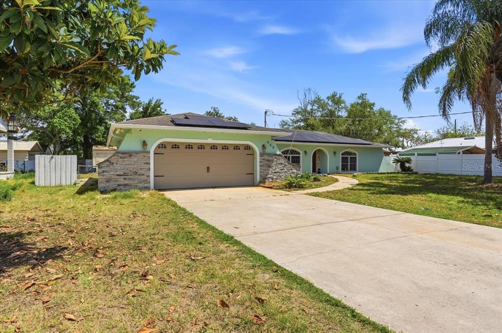 A single-story house with a light green exterior, stone accents, and a concrete driveway — 450 E POMELO STREET, LAKE ALFRED, FL