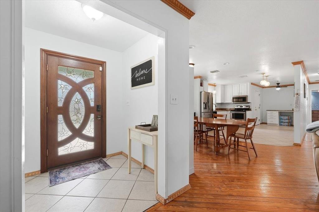 An entryway with a decorative wooden door leads into a dining area and kitchen — 450 E POMELO STREET, LAKE ALFRED, FL