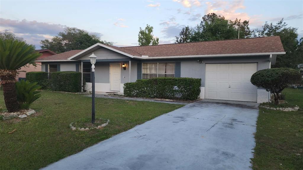 A single-story house with a gray exterior, a shingled roof, and a concrete driveway — 62 SILVER LANE, OCALA, FL