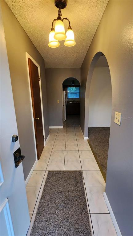 A hallway features light-colored floor tiles, a gray runner rug, and an arched entryway — 62 SILVER LANE, OCALA, FL