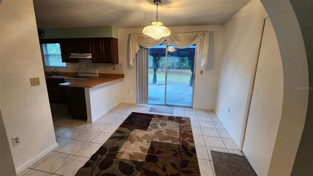 A dining area with tile floors, a patterned rug, and a sliding glass door — 62 SILVER LANE, OCALA, FL