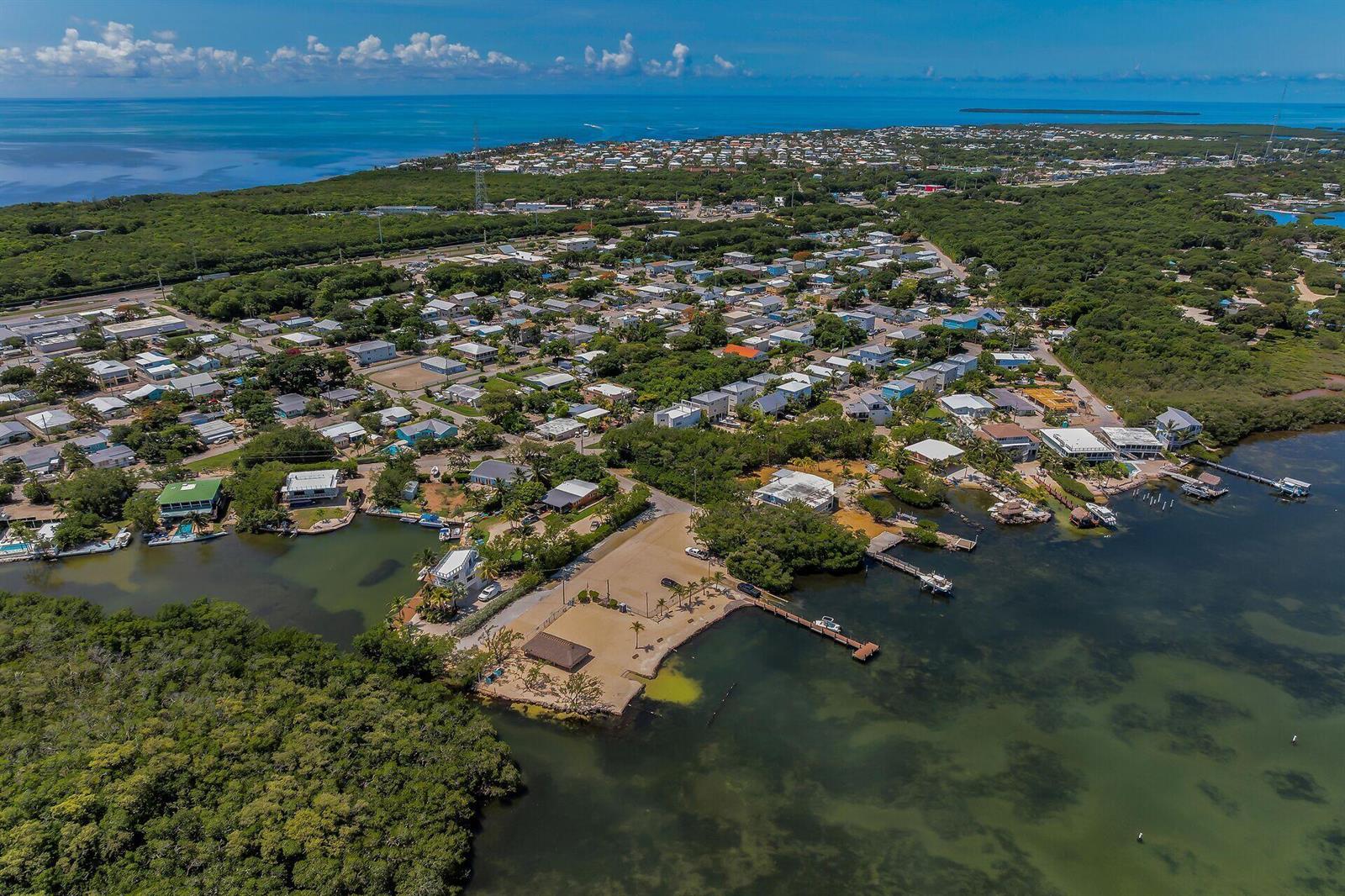 Aerial view of a coastal neighborhood with houses, a small beach, and a wooden dock — 21 Poinciana Drive, Key Largo FL 33037, KEY LARGO, FL