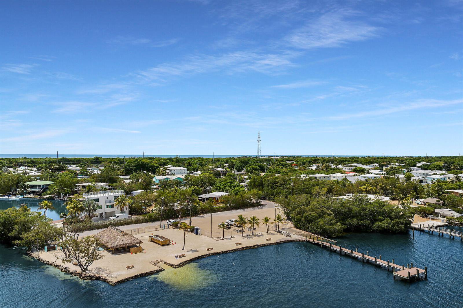 An aerial view shows a waterfront property with a sandy lot, tiki hut, and dock — 21 Poinciana Drive, Key Largo FL 33037, KEY LARGO, FL