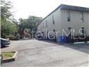 A paved parking lot sits in front of a multi-story, light-colored commercial building — 20 S ROSE AVENUE, KISSIMMEE, FL