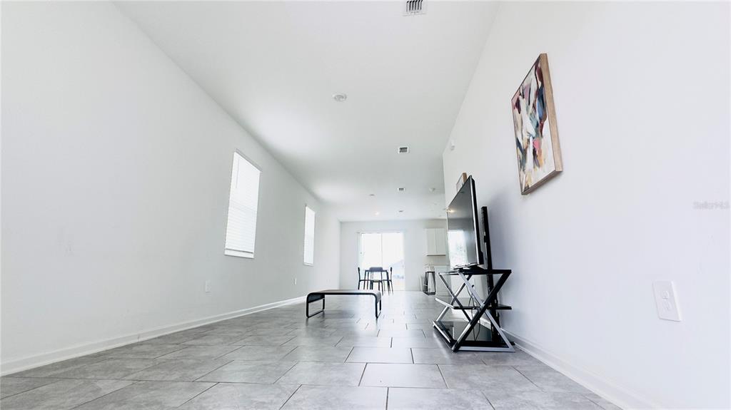 A living room with light gray tile flooring, white walls, and a television on a stand — 3255 LAURENT LOOP, DAVENPORT, FL