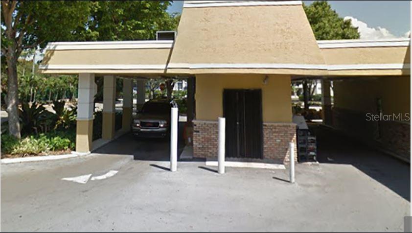 A beige commercial building exterior features a covered drive-through lane with white support pillars — 6900 CYPRESS ROAD, PLANTATION, FL
