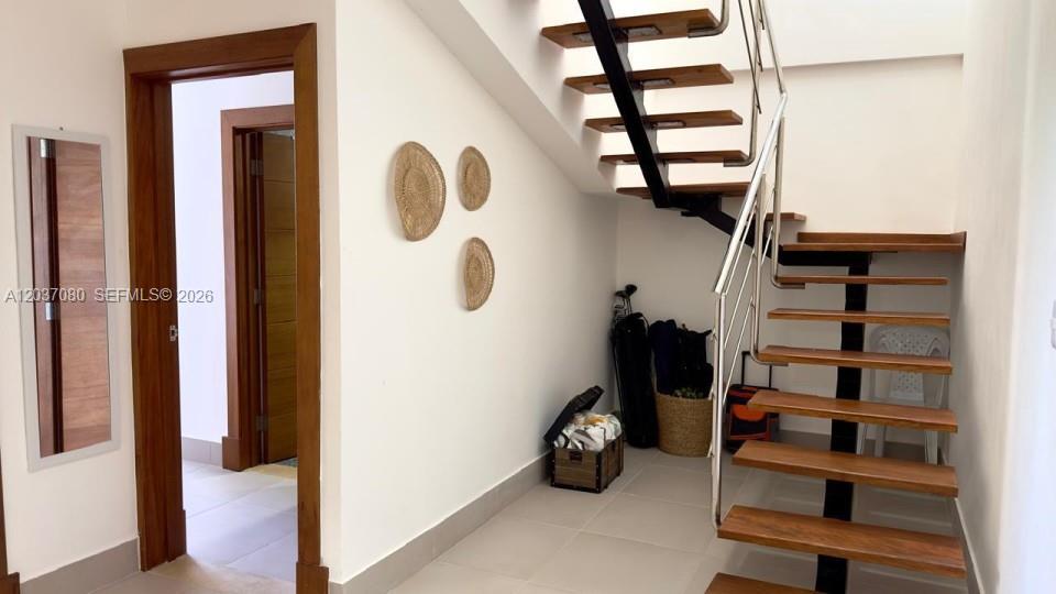 A staircase with wooden treads and a metal railing sits beside a doorway and wall decor — 0 Punta Cana village # 0, FL, FL