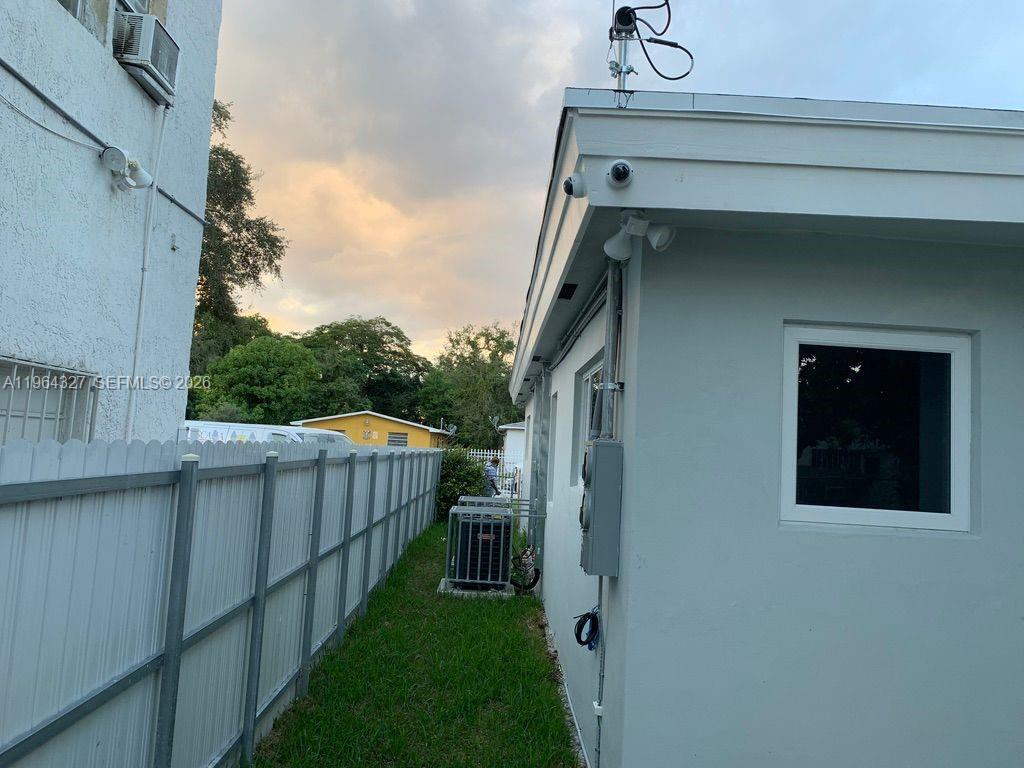 A side view of a house exterior with a fence, lawn, and HVAC unit — 6801 NW 2nd Ct, Miami FL 33150, MIAMI, FL